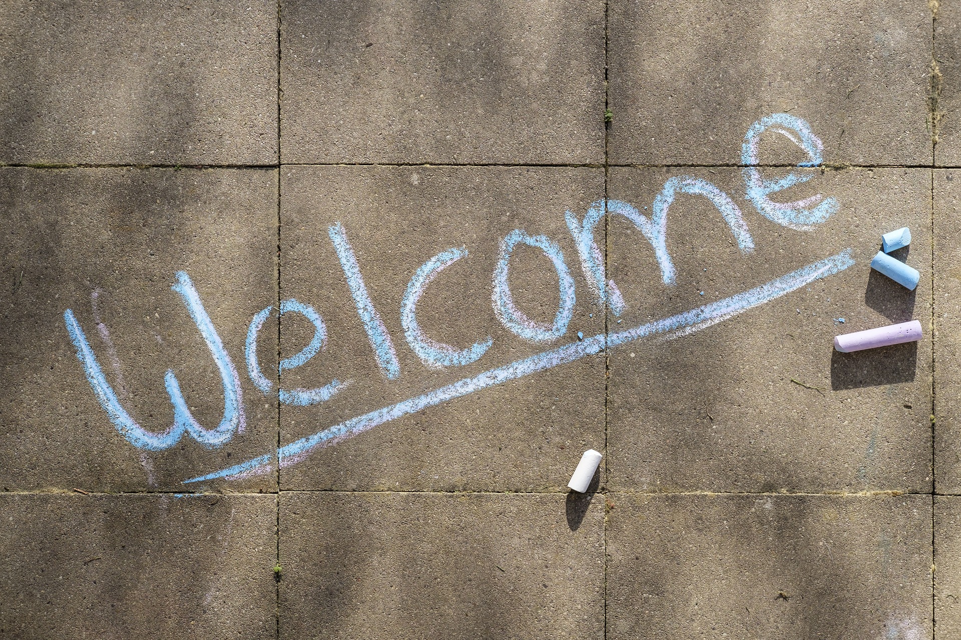 The word 'welcome' written in chalk on the pavement